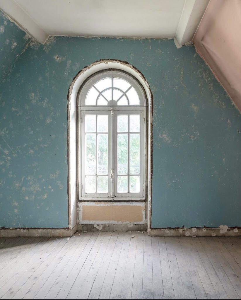 Avant rénovation : pièce avec fenêtre en arc et murs abîmés